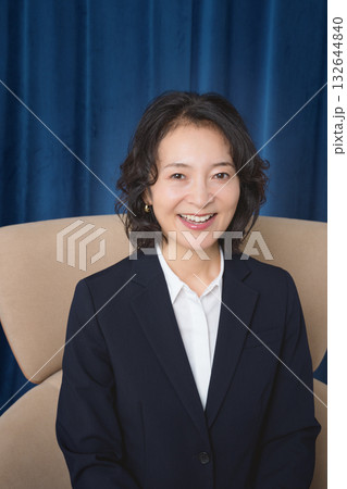 大きな椅子に座るミドルビジネスウーマン 132644840
