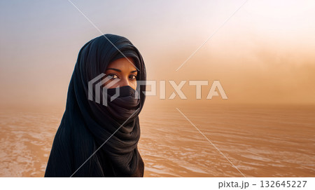 Sandstorm and a woman in a burqa in the desert. Climate change in Africa is causing a terrible sandstorm, carrying mud and sand across the savannah, disrupting normal life. 132645227