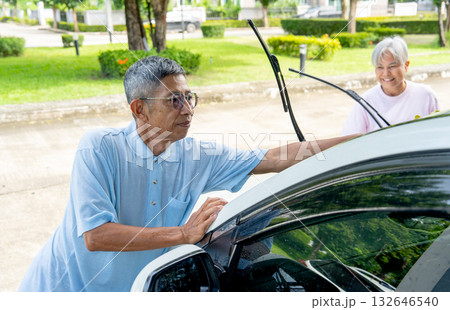 Asian senior man use car towel to clean his car with senior woman and look happiness in front of their house. Asian senior man use car towel to clean his car with senior woman and look happiness in front of their house. 132646540