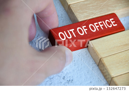 Hand pulling out a red wooden block with out of office text on. Getaway or on a vacation concept. 132647273