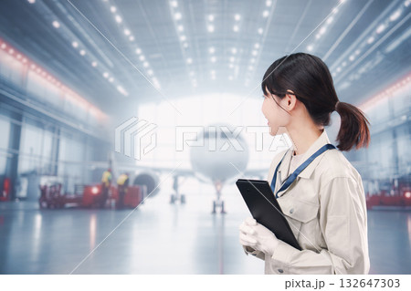 飛行機の格納庫で働く技術者の若い女性 飛行機の格納庫で働く技術者の若い女性 132647303