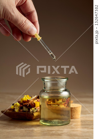 Dropping essential oil or herbal tincture into a glass bottle. Dropping essential oil or herbal tincture into a glass bottle. 132647382