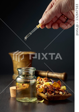 Dropping essential oil or herbal tincture into a small bottle. 132647383