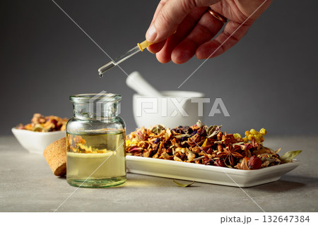 Dropping essential oil or herbal tincture into a glass bottle. 132647384