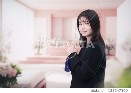お葬式で合掌をする喪服を着た若い女性 132647509