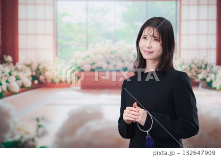 お葬式で喪服を着て数珠を持つ若い女性 132647909