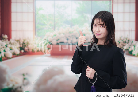 お葬式で喪服を着て数珠を持つ若い女性 132647913