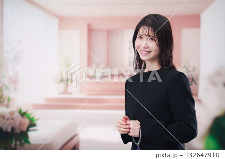 お葬式で喪服を着て数珠を持つ若い女性 132647918