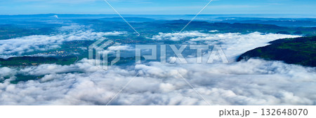 Beautiful landscape of rolling clouds covering the valley with distant mountains and clear blue sky Beautiful landscape of rolling clouds covering the valley with distant mountains and clear blue sky 132648070