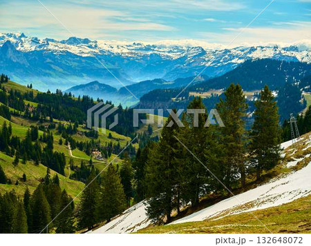 Scenic mountain landscape showcasing lush green valleys and distant snow-capped peaks near the Swiss Alps in springtime 132648072