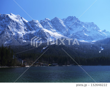 Snowy mountain range reflects in clear lake during sunny day, showcasing natural beauty and outdoor adventure Snowy mountain range reflects in clear lake during sunny day, showcasing natural beauty and outdoor adventure 132648222