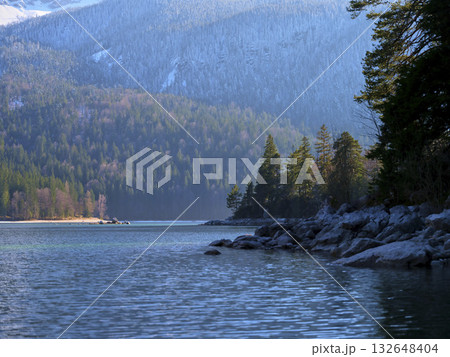 Calm waters reflect the serene landscape of mountains and trees during a crisp morning in a tranquil natural setting Calm waters reflect the serene landscape of mountains and trees during a crisp morning in a tranquil natural setting 132648404