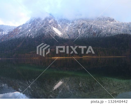 Snow-capped mountains reflect in tranquil lake during early morning hours in a serene outdoor landscape Snow-capped mountains reflect in tranquil lake during early morning hours in a serene outdoor landscape 132648442