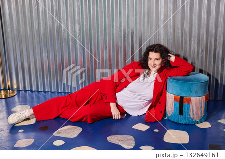 playful lady in red suit lounging comfortably, relaxed woman with curly red hair enjoying leisure playful lady in red suit lounging comfortably, relaxed woman with curly red hair enjoying leisure 132649161