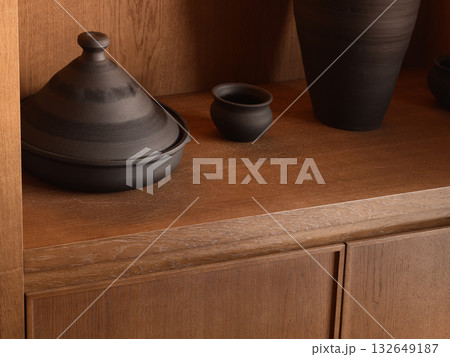 naturaltoned ceramic vessels on wooden cabinet illuminated by warm directional light creating cozy naturaltoned ceramic vessels on wooden cabinet illuminated by warm directional light creating cozy 132649187