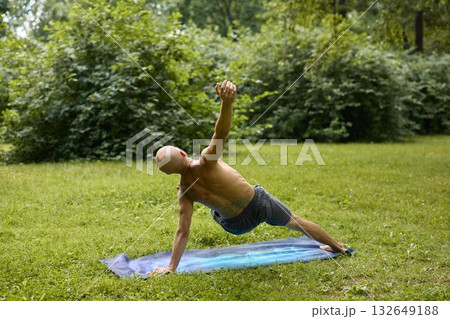 A man is practicing yoga in a serene natural setting, embracing the peaceful ambiance 132649188