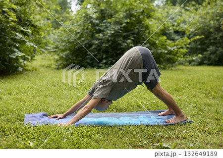 A Person Engaged in Practicing Yoga Outdoors in Nature Specifically in the Downward Dog Pose A Person Engaged in Practicing Yoga Outdoors in Nature Specifically in the Downward Dog Pose 132649189
