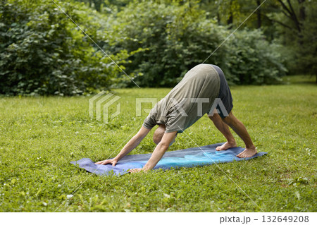 A Person Practicing Yoga in Nature Demonstrating the Downward Dog Pose Outside 132649208
