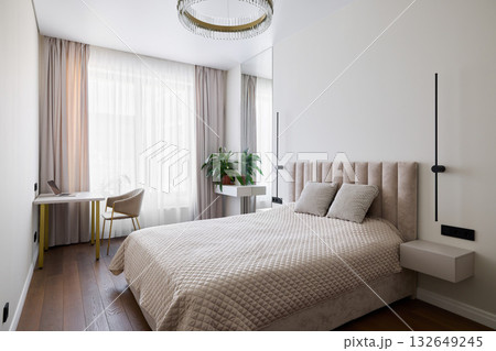 A modern, cozy bedroom with stylish decor and a functional workspace for productivity A modern, cozy bedroom with stylish decor and a functional workspace for productivity 132649245