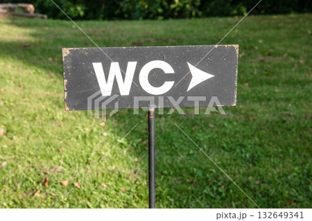 Black WC sign with white letters and arrow pointing direction, mounted on a metal post in grassy Black WC sign with white letters and arrow pointing direction, mounted on a metal post in grassy 132649341