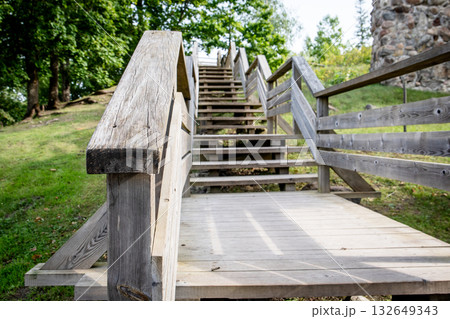 Rustic wooden staircase with railings leading uphill in a natural park setting 132649343