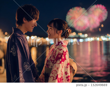 夏の花火と水辺で向かい合い微笑み合う浴衣姿の若い日本人カップルのロマンチックな光景 132649669