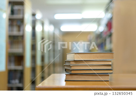 Book stack in the library and blurred bookshelf background for education Book stack in the library and blurred bookshelf background for education 132650345