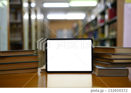 Stack of books with empty screen digital tablet in library Stack of books with empty screen digital tablet in library 132650372
