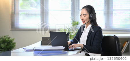 Smiling businesswoman wearing headset talking during online meeting, representing customer service support and communication in modern office 132650402