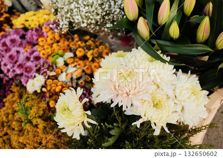 Closeup of blooming chrysanthemums and tulip buds in a colorful flower display. Street spring outdoor market 132650602