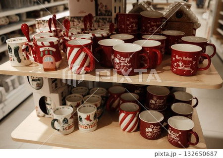 Festive ceramic mugs with red and white Christmas patterns displayed on a store shelf 132650687