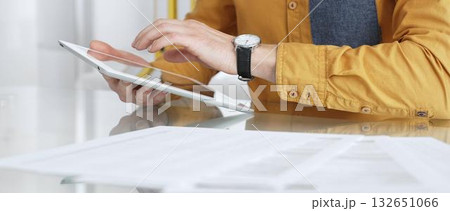 Person using a digital tablet for business at desk, navigating online content or browsing documents. Audit and taxes in business Person using a digital tablet for business at desk, navigating online content or browsing documents. Audit and taxes in business 132651066