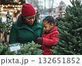 Mother and daughter choose a Christmas tree at a market. 132651852