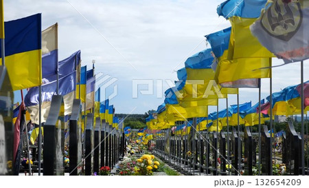 View on countless graves of ukrainian soldiers alley of glory in Kharkiv decorated with waving blue-yellow flags. The site commemorates soldiers who died during russian invasion in Ukraine. Slow mo 132654209