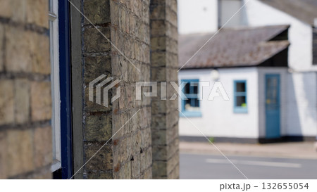 Brick wall framing a blurred view of a small house in Cambridge, UK 132655054