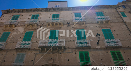 Sun shining on traditional building with green shutters in Tropea, Italy Sun shining on traditional building with green shutters in Tropea, Italy 132655295