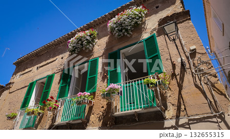 Green window shutters and colorful flowers decorating building facade in Tropea, Italy 132655315