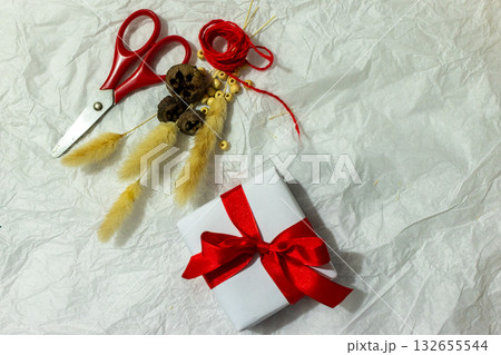 Homemade holiday gift surrounded by rustic natural decorations,yarn, scissors, and cozy seasonal accents. 132655544