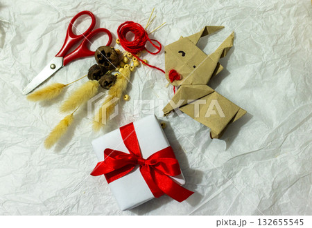 Christmas gift is made by hand ,surrounded by rustic natural decorations, origami reindeer and Christmas ornaments. Christmas gift is made by hand ,surrounded by rustic natural decorations, origami reindeer and Christmas ornaments. 132655545