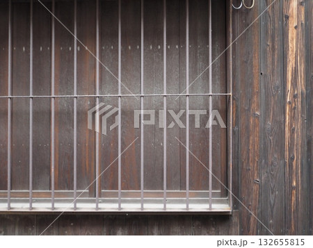 古民家の黒ずんだ木製雨戸と、重厚な縦格子が並ぶ窓のクローズアップ 132655815