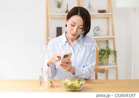 スマホを見ながら食事する女性 スマホを見ながら食事する女性 132656197