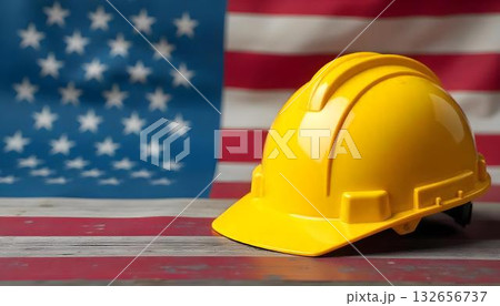 A construction helmet sits on a table with an American flag, highlighting Labor Day and the importance of various professions A construction helmet sits on a table with an American flag, highlighting Labor Day and the importance of various professions 132656737