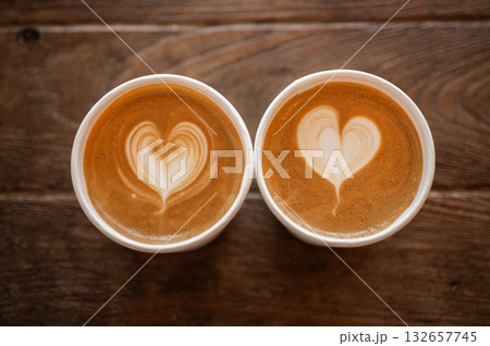 Couple cups of cappuccino coffee on wooden table. A cappuccino is the perfect balance of espresso, steamed milk and foam. Couple cups of cappuccino coffee on wooden table. A cappuccino is the perfect balance of espresso, steamed milk and foam. 132657745
