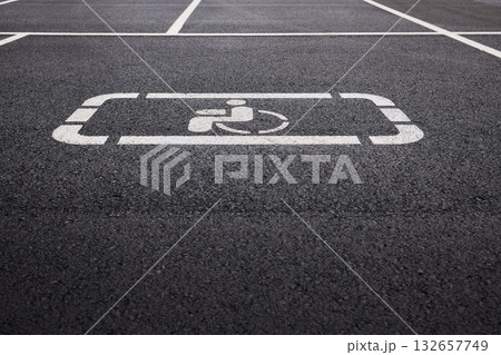 car parking space on asphalt, white worn markings, textured pavement, Handicap sign represents accessibility, inclusivity, equal rights, and consideration for individuals with disabilities 132657749