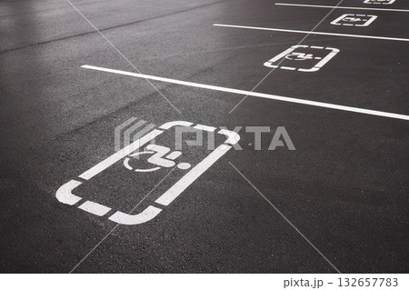 car parking space on asphalt, white worn markings, textured pavement, Handicap sign represents accessibility, inclusivity, equal rights, and consideration for individuals with disabilities car parking space on asphalt, white worn markings, textured pavement, Handicap sign represents accessibility, inclusivity, equal rights, and consideration for individuals with disabilities 132657783