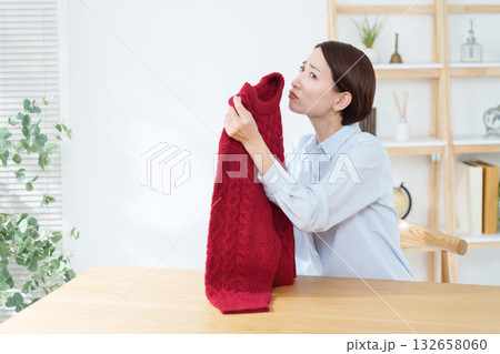 衣替えで出したセーターの臭いを嗅ぐ女性 衣替えで出したセーターの臭いを嗅ぐ女性 132658060