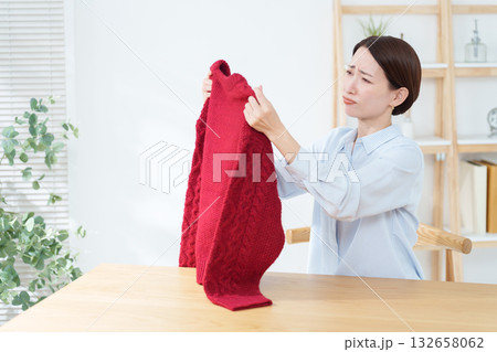 衣替えで出したセーターに問題を見つけた女性 132658062