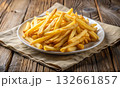 Golden French fries on a white plate placed on a cloth napkin 132661857