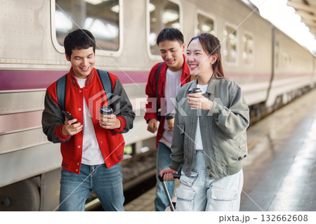 Travel Companions. Friends walking together at a train station with coffee. Travel Companions. Friends walking together at a train station with coffee. 132662608