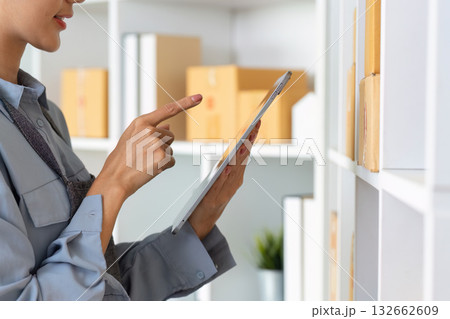 Small Business Management. Professional woman organizing inventory with tablet in modern workspace. Small Business Management. Professional woman organizing inventory with tablet in modern workspace. 132662609